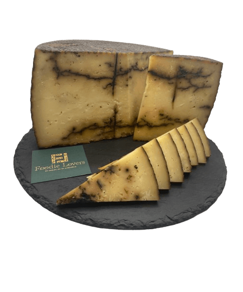 Queso de oveja curado con ajo negro, con textura firme y cremosa, presentado en cuñas envasadas al vacío para preservar su frescura y calidad. Ideal para aperitivos gourmet y maridajes con vino tinto